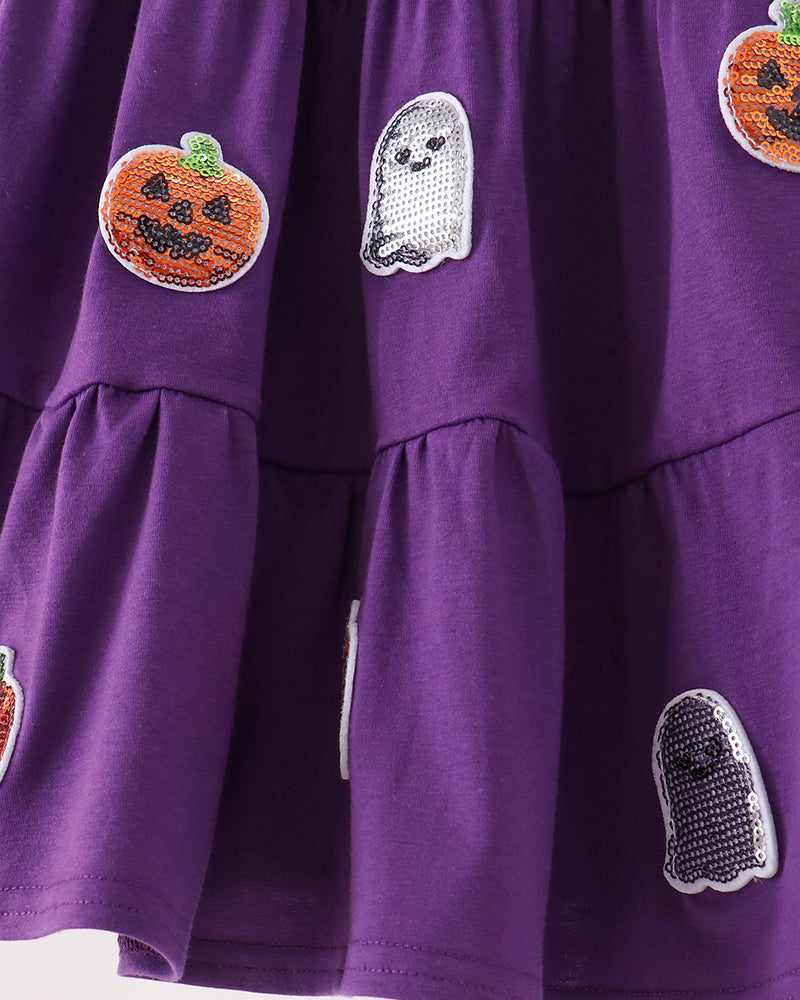A close-up of a purple tiered dress decorated with sequined ghost and pumpkin patches.