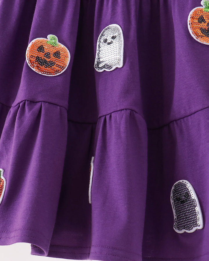 A close-up of a purple tiered dress decorated with sequined ghost and pumpkin patches.
