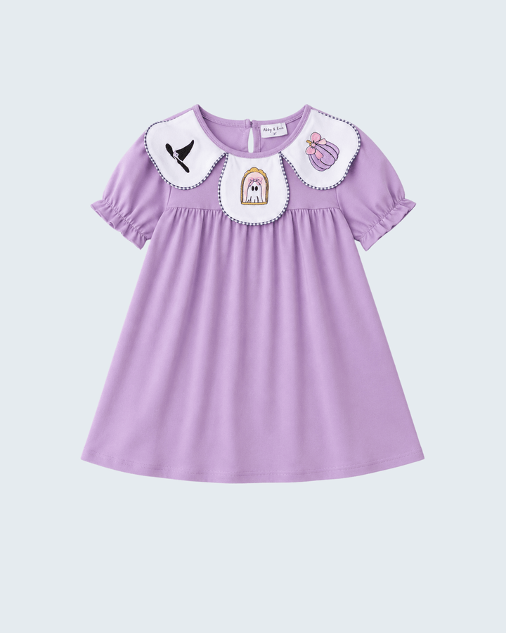 A lavender purple short-sleeve dress for toddlers, featuring a white Peter Pan collar decorated with embroidered whimsical characters (a bird, a ghost, and a perfume bottle) on a light gray background.