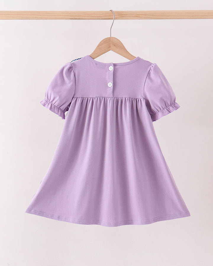 A light purple short-sleeve baby dress with puff sleeves and a gathered waist, hanging on a wooden hanger against a plain off-white background.