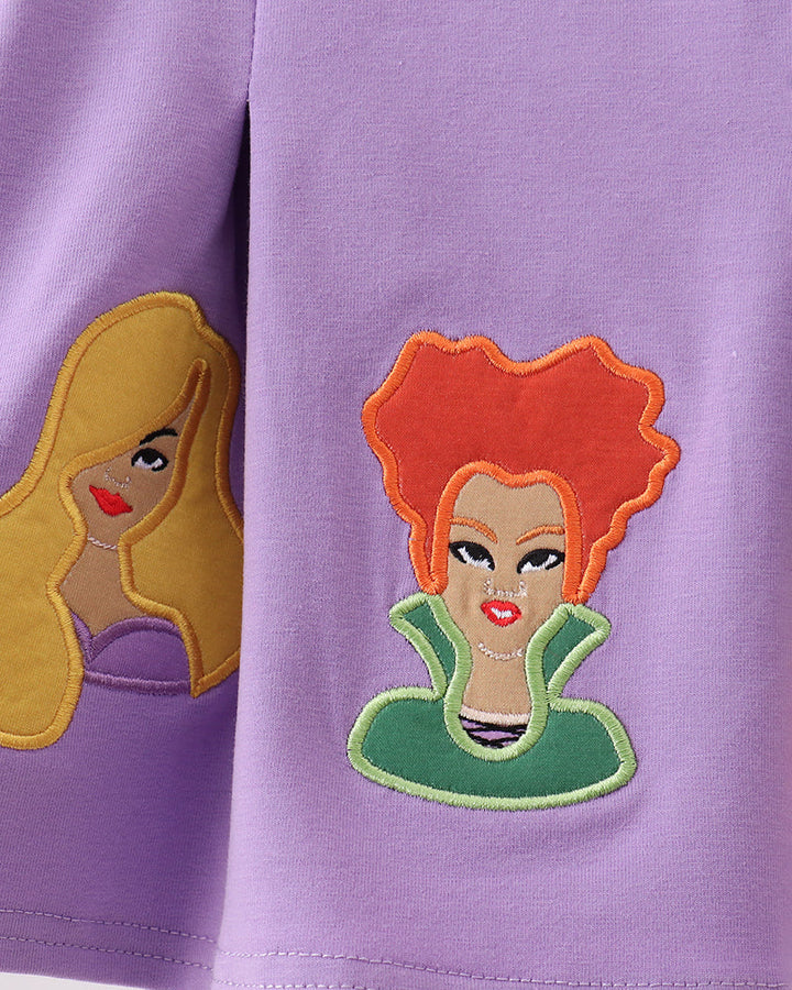 Purple tunic with witch face appliques in yellow, orange, and green thread