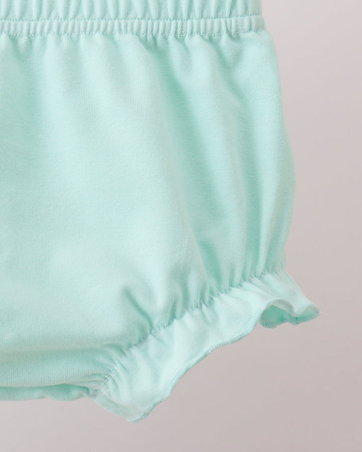 Mint green baby bloomers on a light pink background