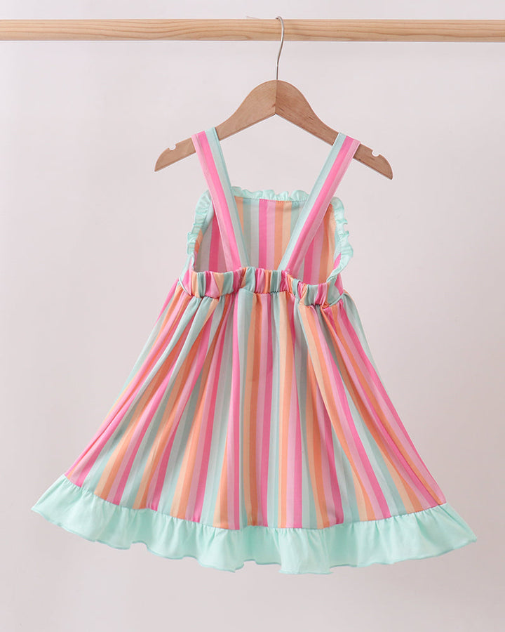 Colorful striped dress on a hanger against a light pink background