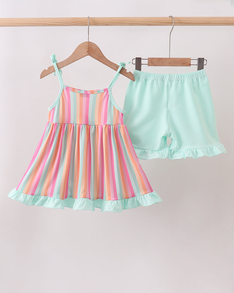 Striped dress and shorts set on hangers against a light pink background