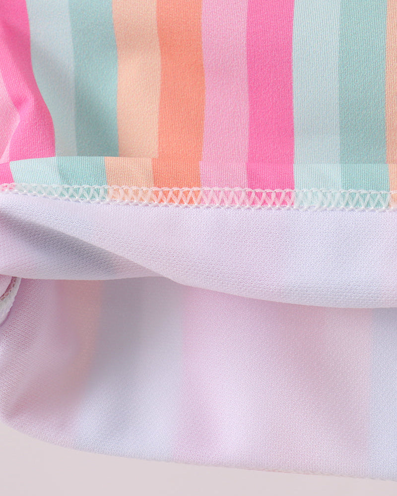 Close-up of a fabric with colorful striped pattern on a light pink background