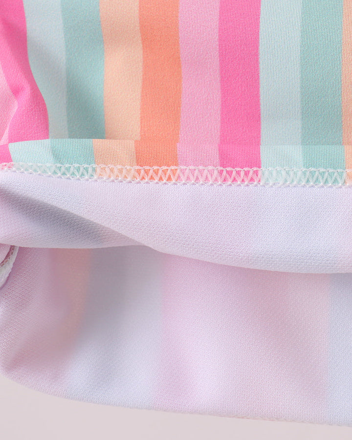 Close-up of a fabric with colorful striped pattern on a light pink background