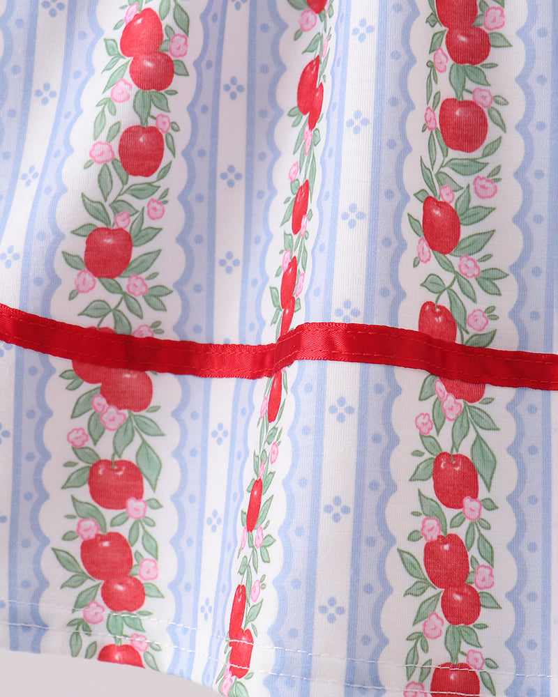 Dress with apple pattern and red ribbon on a blue and white striped background