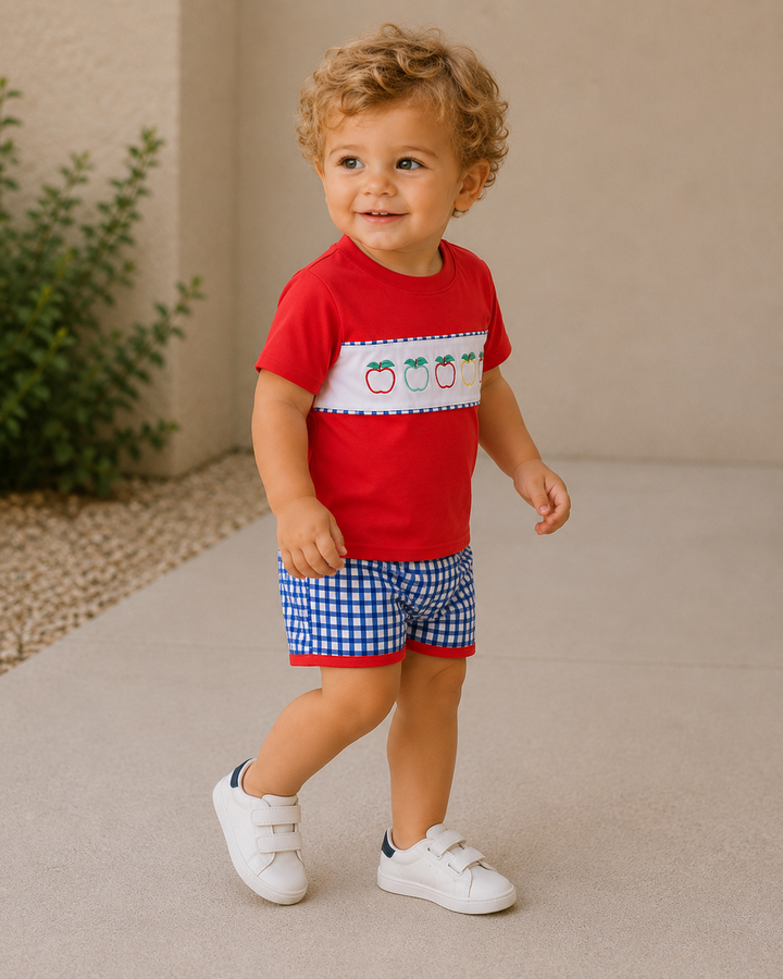 Toddler boy walking outside. He is wearing an apple shirt