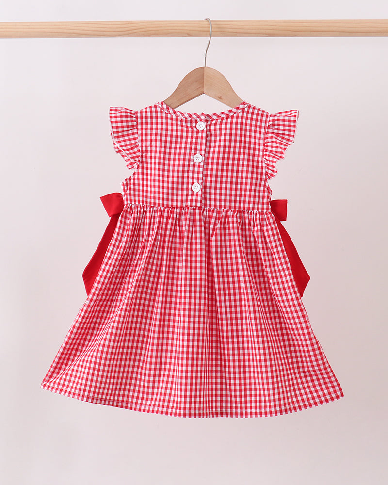 Red checkered dress with red bows on a hanger against a white background
