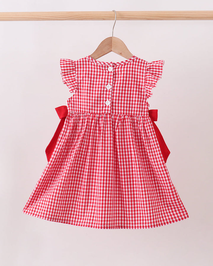 Red checkered dress with red bows on a hanger against a white background