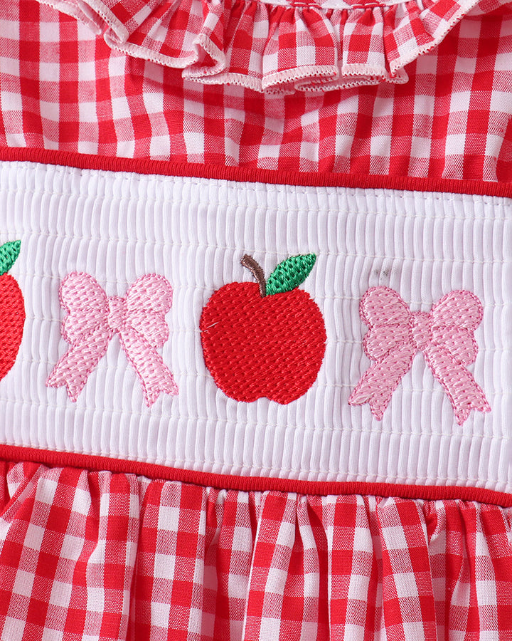 Red and white checkered dress with apple and bow designs on a white background