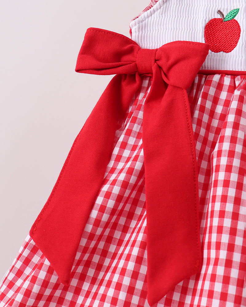 Red and white checkered dress with a large bow and apple applique on a light gray background