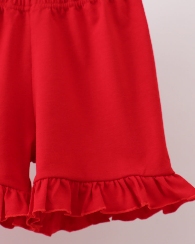 Red shorts with ruffled hem on a light gray background