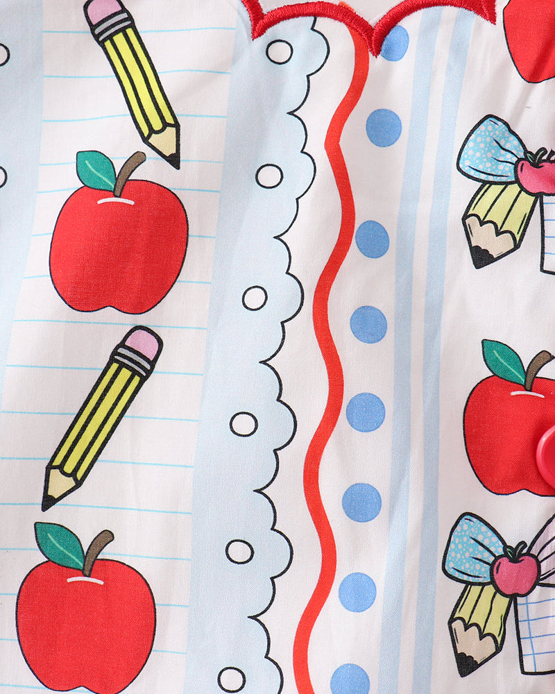Close-up of white top with apple and pencil print, red scalloped trim and blue dots