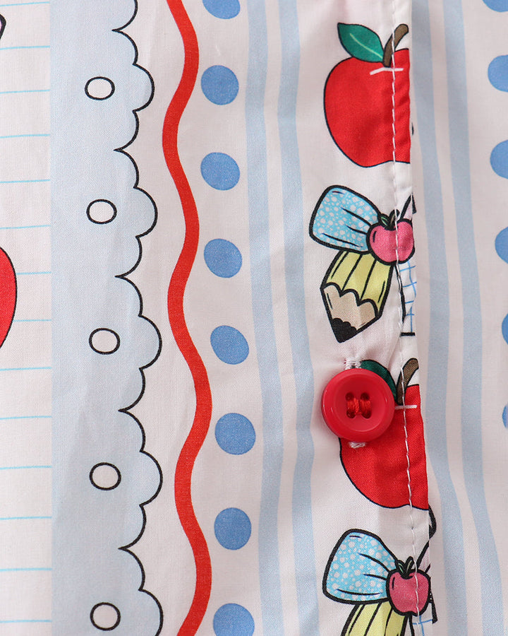 Close-up of printed top fabric with apple and cupcake graphics and red buttons