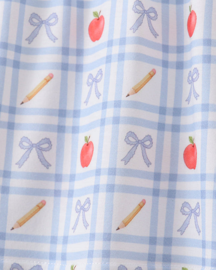 Close-up of blue gingham top with scattered apple, bow and candy stick motifs