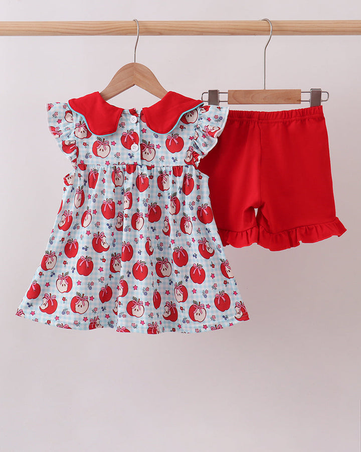 Apple-print dress and red shorts set on hangers, front view
