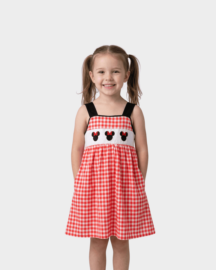 Young girl in a character embroidered red plaid dress. Neutral background