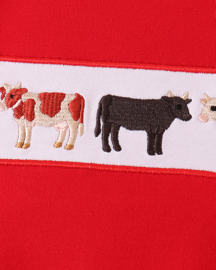 Close-up of animal embroidery band with cow and farm animals on red fabric