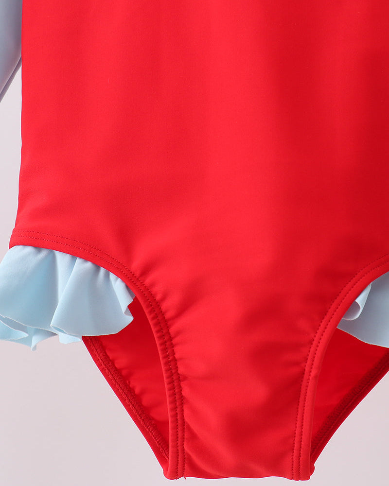 Red swimsuit with ruffled trim on a light gray background