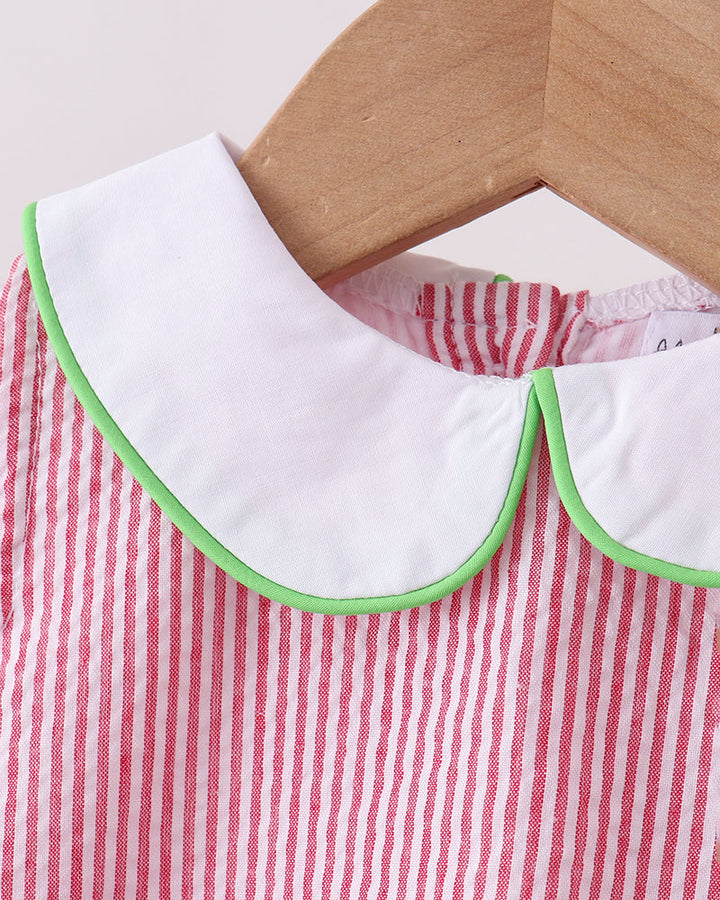 Red and white striped dress with a white collar and green trim on a wooden hanger.