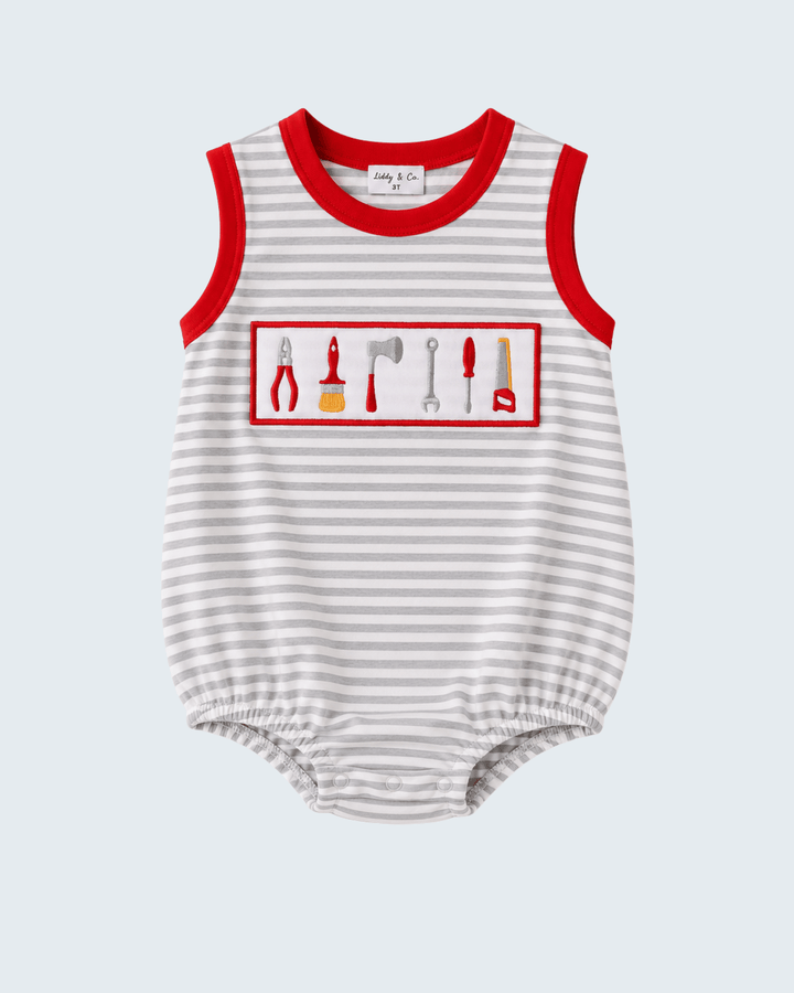 A sleeveless baby romper with thin gray and white horizontal stripes, red trim at the collar and armholes, and a chest graphic showing various hand tools inside a red rectangular border.