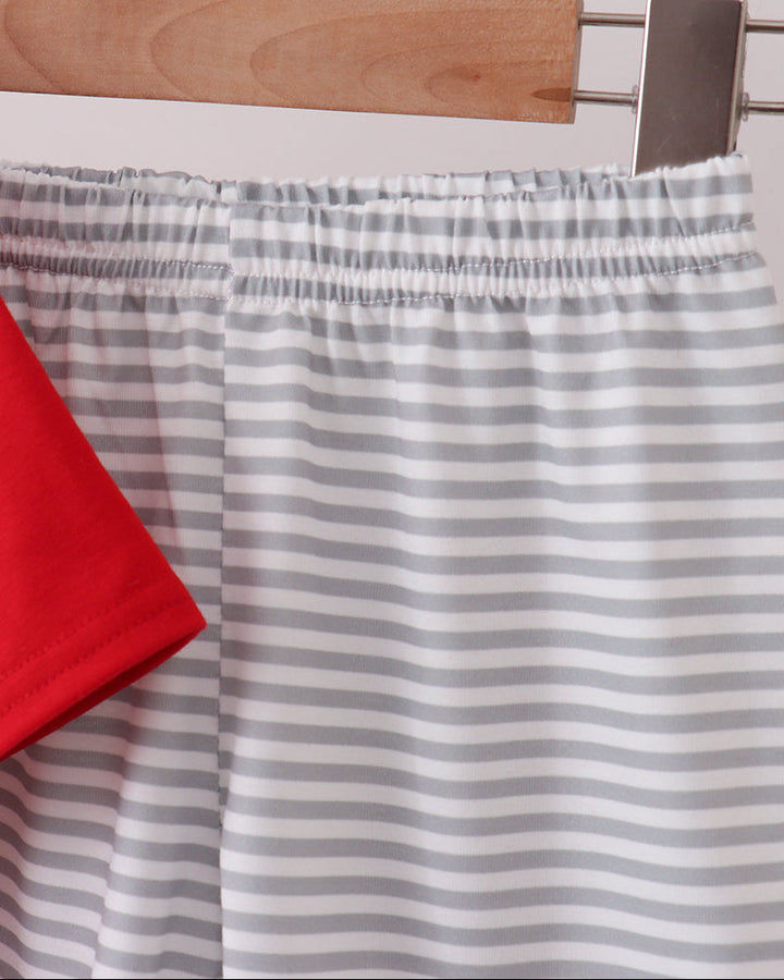 Gray and white striped shorts with an elastic waistband, hanging on a wooden hanger with a red garment partially visible on the left.