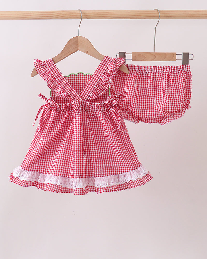 Red and white checkered dress with matching bloomers on a hanger against a beige background