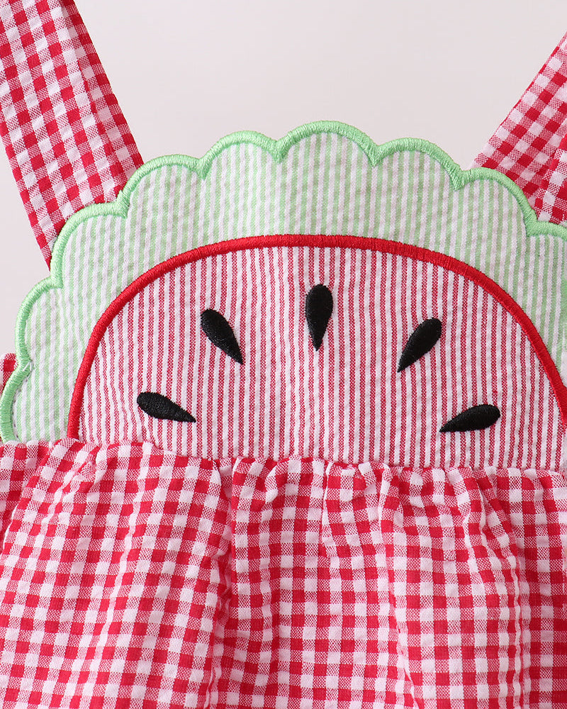 Red and white checkered romper with watermelon design on a wooden surface