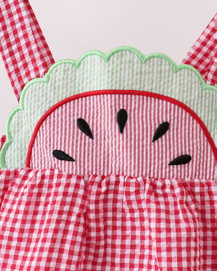Red and white checkered romper with watermelon design on a wooden surface