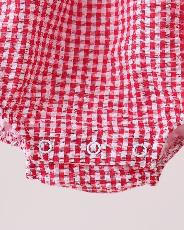 Red and white checkered baby romper with buttons on a light gray background