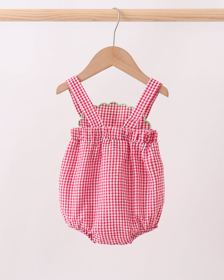 Red and white checkered baby romper on a wooden hanger against a light background