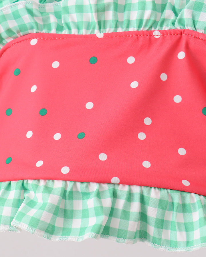 Swim set with pink polka dot top and green checkered bottom on a light gray background