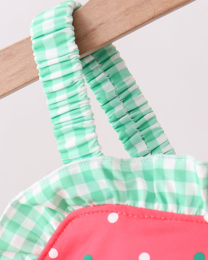 Green and white checkered bikini top with pink bottom on a wooden hanger.