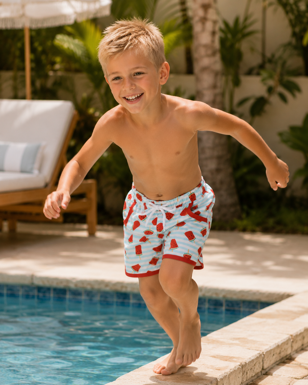 Child in swim shorts standing on a pool edge with a pool and lounge chair in the background