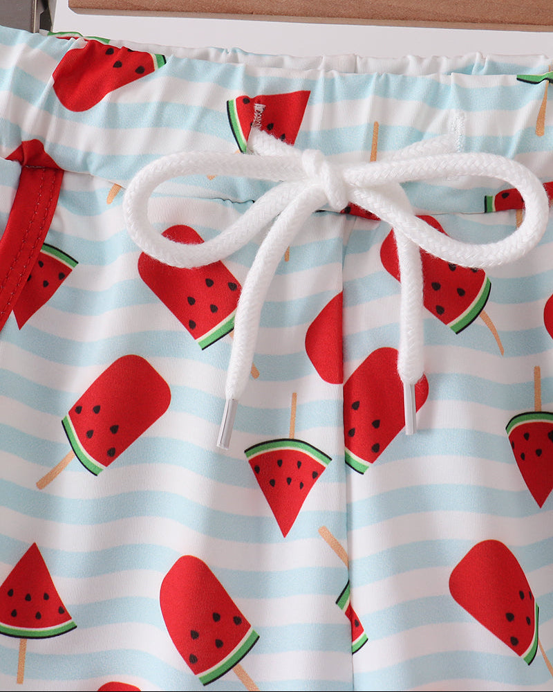 Shorts with watermelon pattern on a hanger against a white background