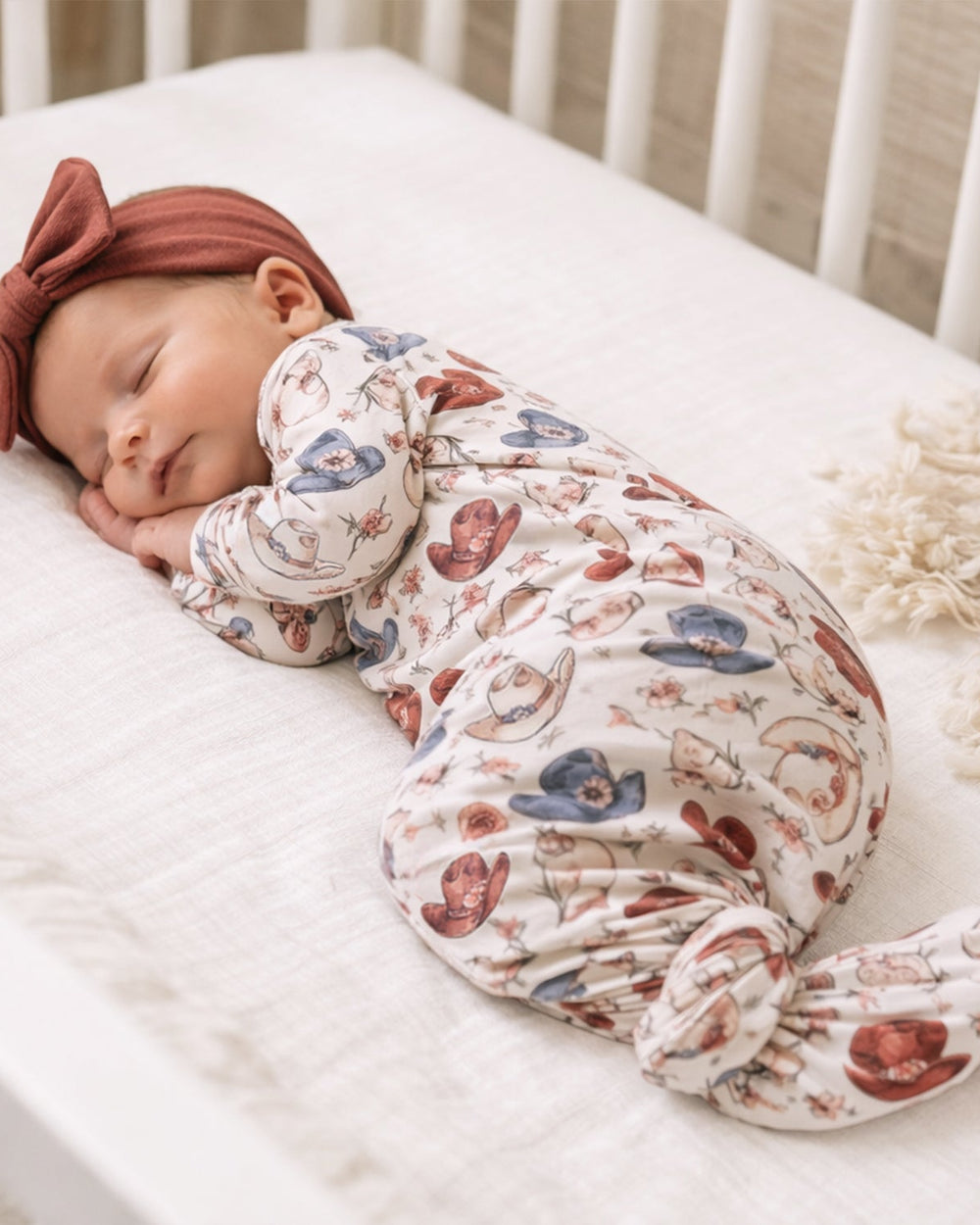 Newborn footed gown, cream with rodeo-themed cowboy print and matching knotted cap