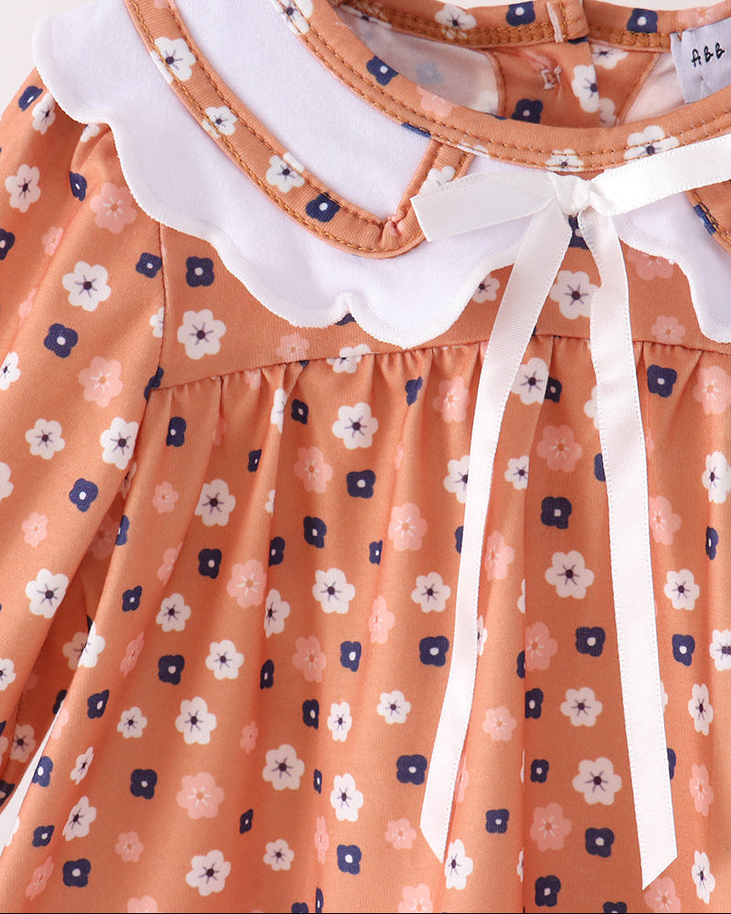 Close-up of white Peter Pan collar bow on rust floral dress with gathered skirt