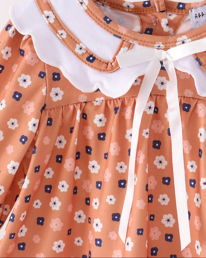 Close-up of white Peter Pan collar bow on rust floral dress with gathered skirt