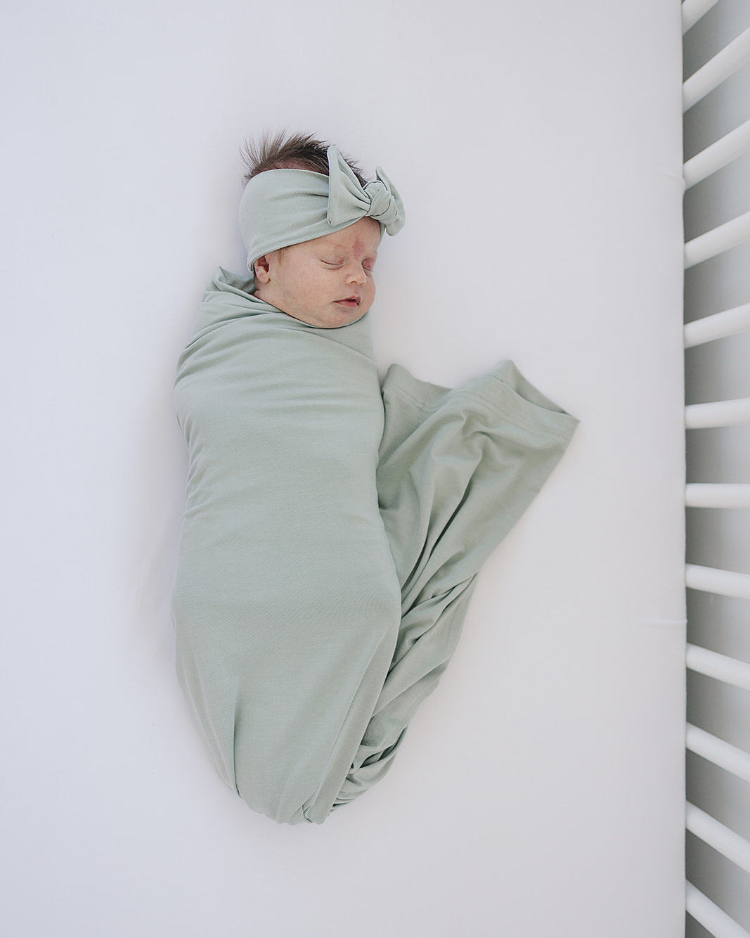 Sage green knotted head wrap turban-style, worn by a baby