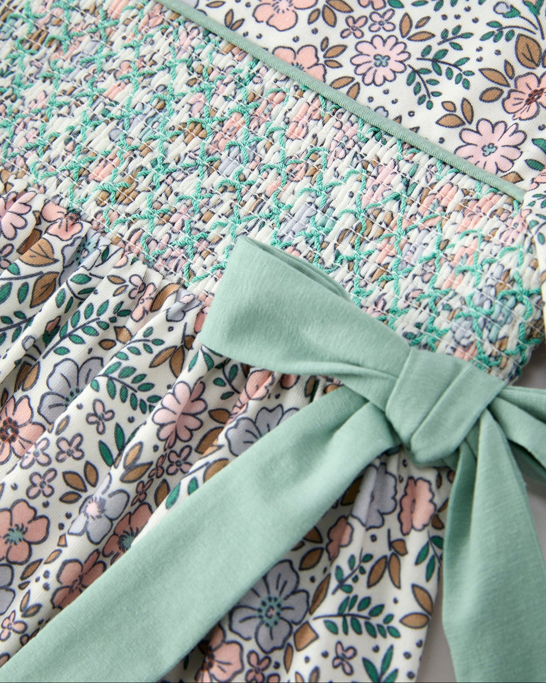 Close-up of floral smocked bodice with sage ribbon bow