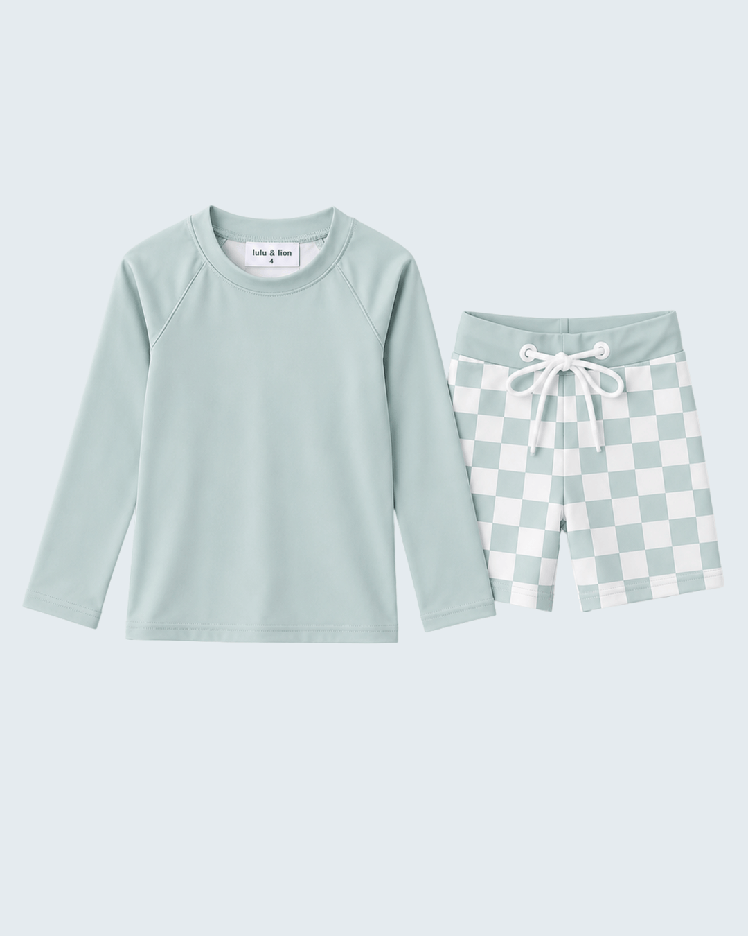 Swim set with mint green long-sleeve top and checkered shorts on a light blue background.
