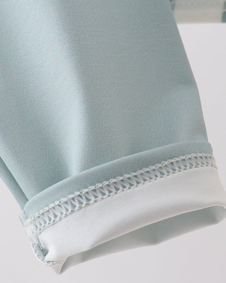 Close-up of light blue fabric with white trim on a white background