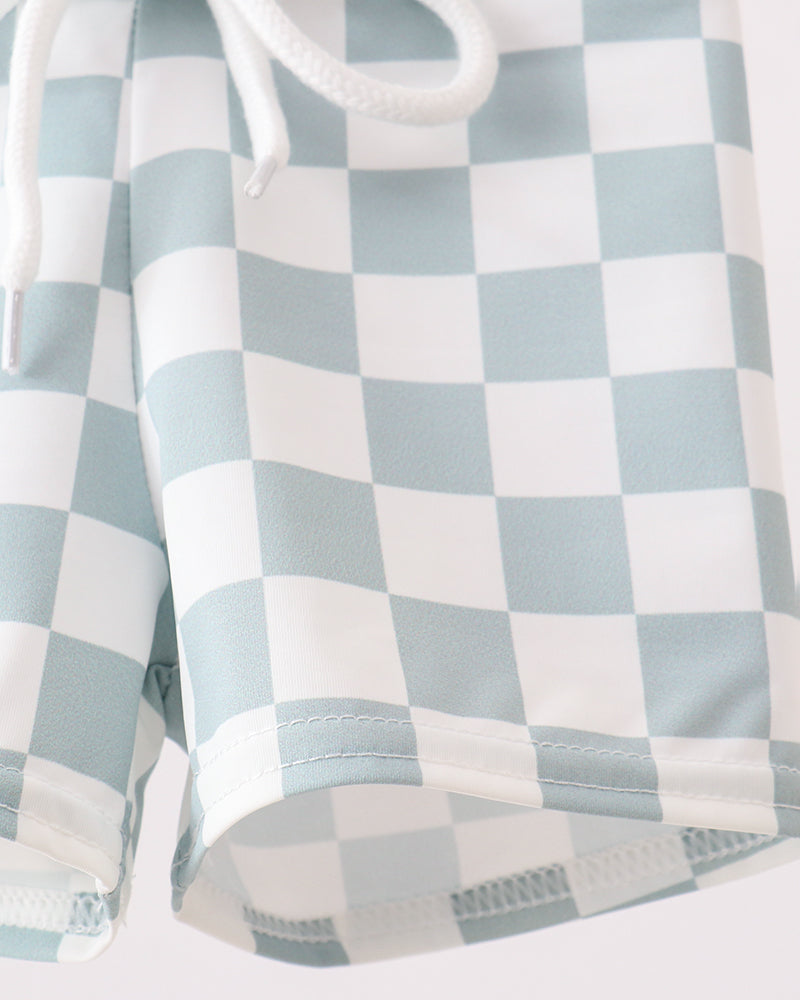 Checkered swim trunks with light blue and white pattern on a plain background