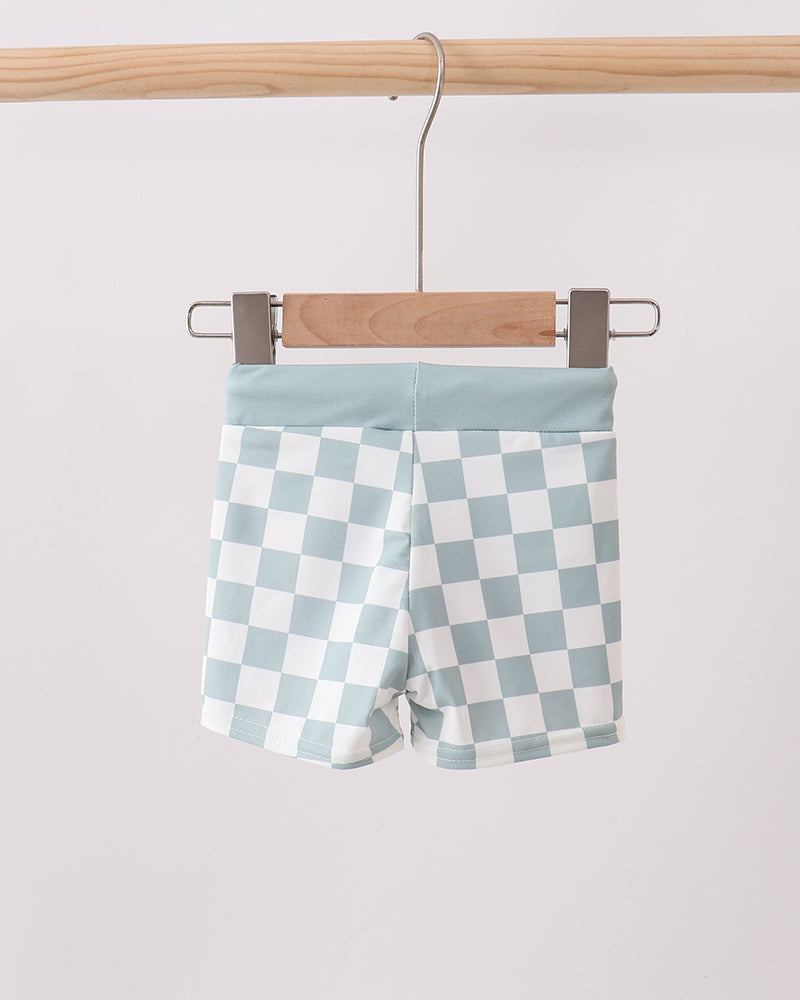 Checkered shorts hanging on a wooden hanger against a white background