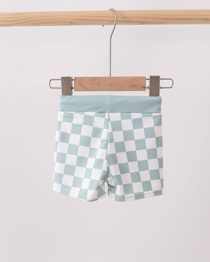 Checkered shorts hanging on a wooden hanger against a white background