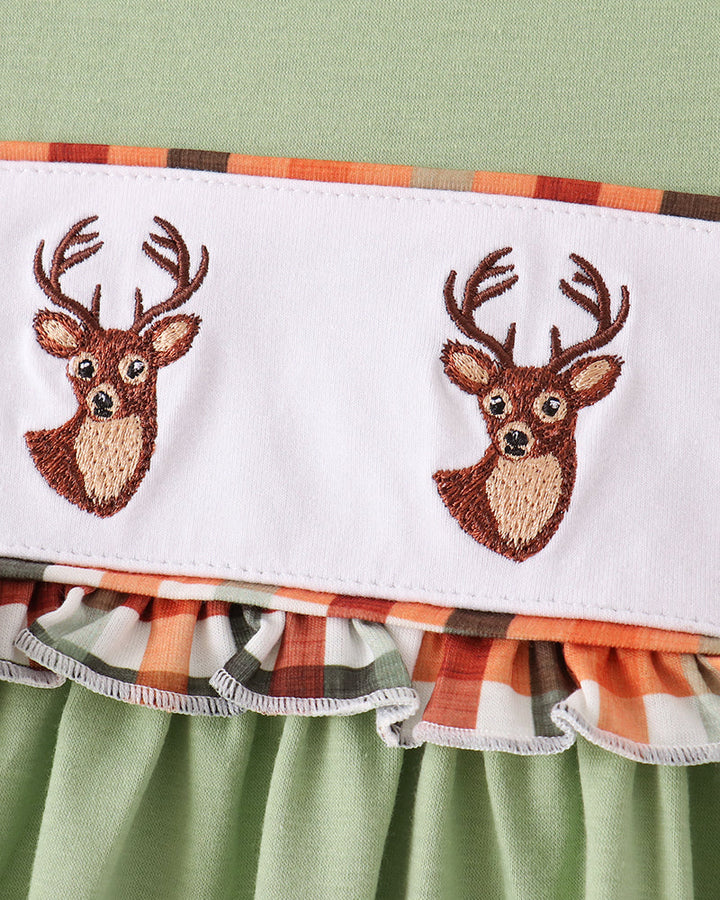 Close-up of embroidered deer faces on white yoke panel with ruffle trim