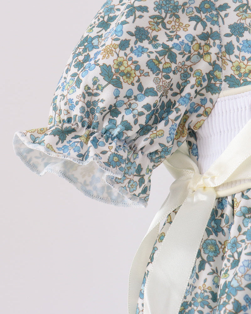 Blue floral bubble romper with smocked bodice, ruffled sleeves and scalloped hem