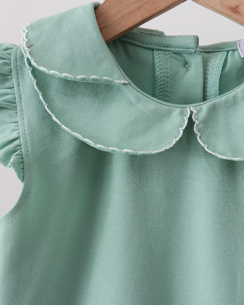 Green dress with a ruffled collar on a wooden hanger against a light background