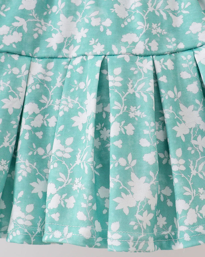Close-up of a turquoise skirt with white floral pattern on a light gray background